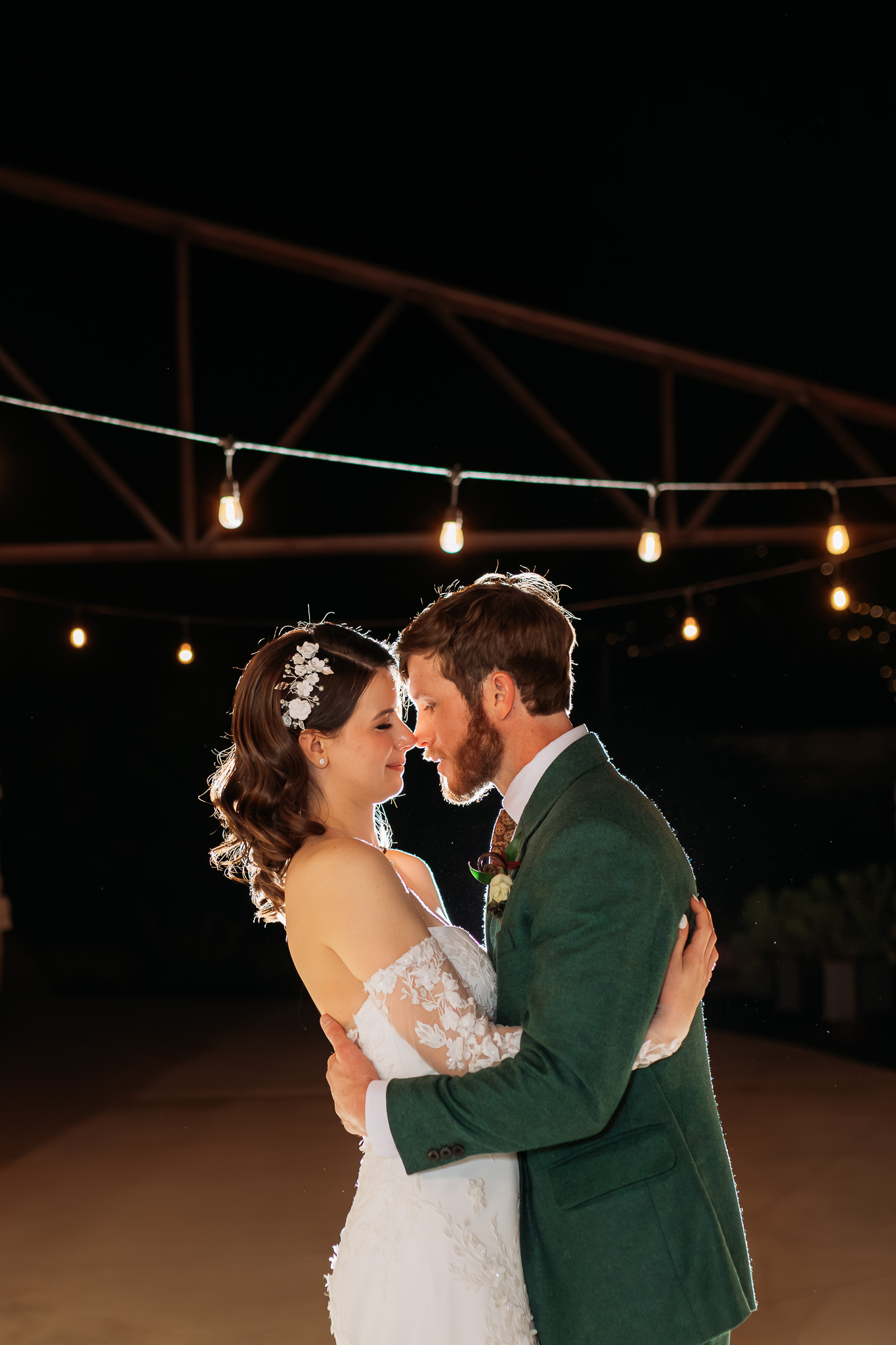 Bride and groom embracing under string lights at Park 31 wedding reception in Spring Branch Texas